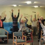 Group doing exercise class with arms in the air